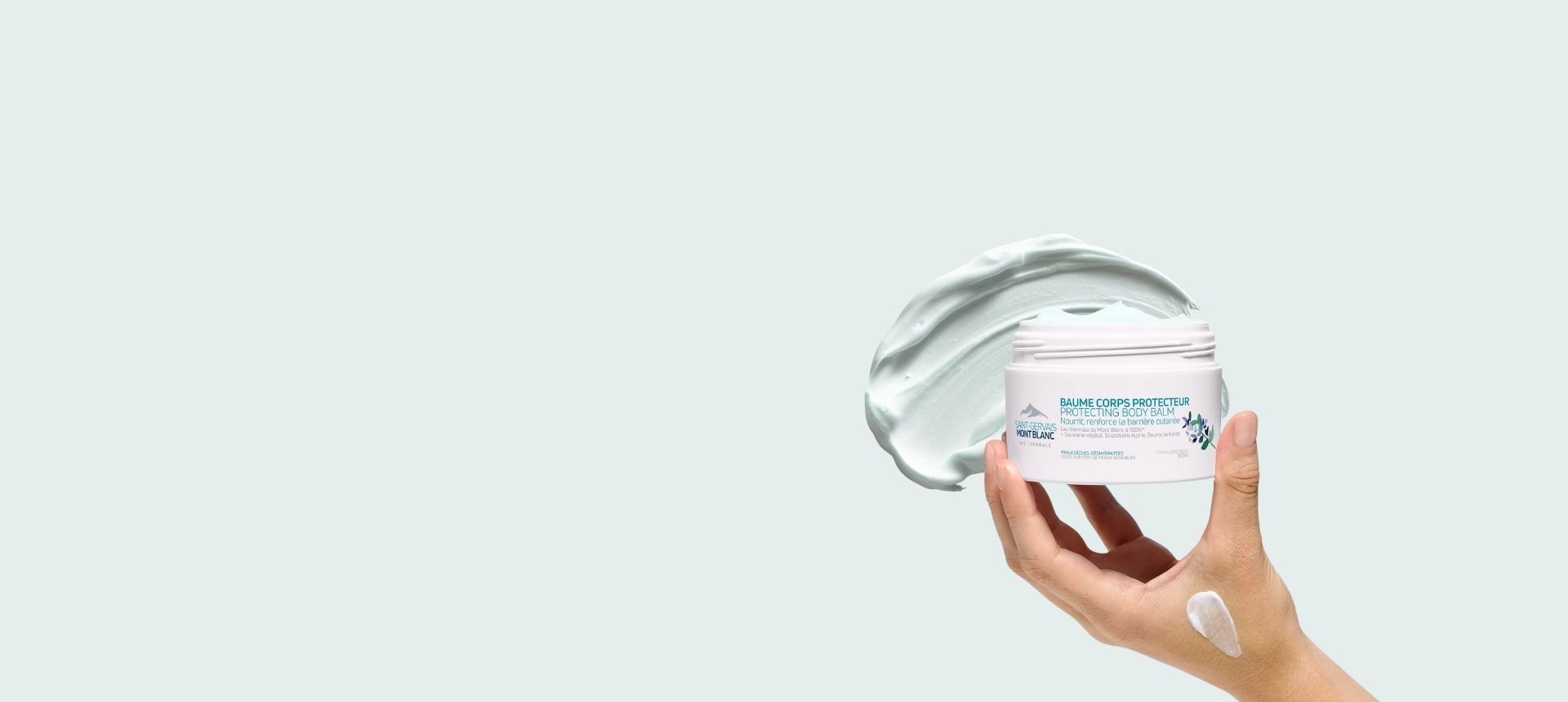 Main tenant le Baume corps fondant Saint-Gervais Mont Blanc sur une texture crème