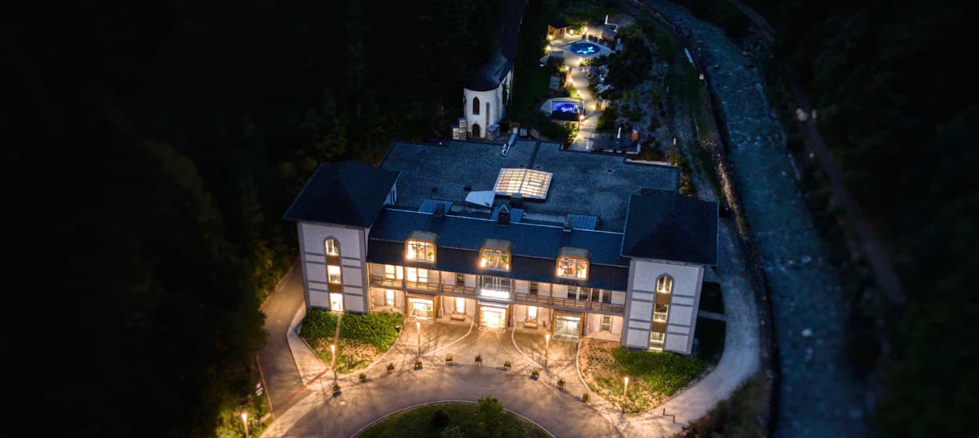 Vue aérienne des Thermes de Saint-Gervais-les-Bains illuminés à la nuit tombée.