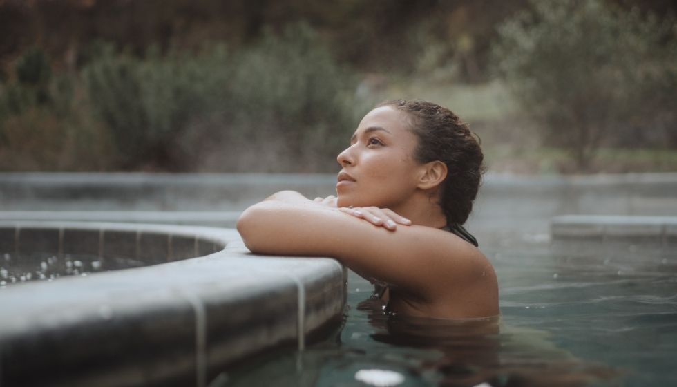 Femme détendue dans un bassin d'eau thermale chaude extérieur