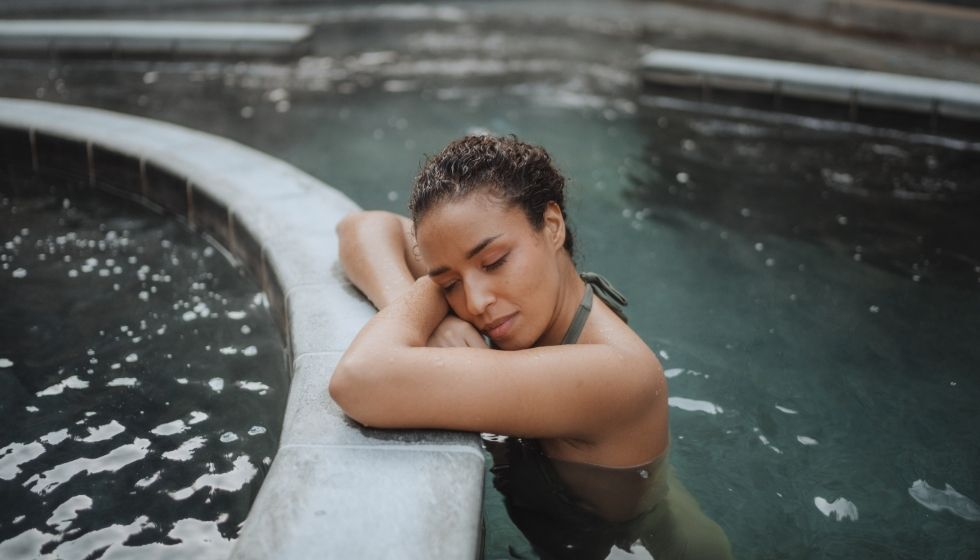 Femme se prélassant dans un bassin d'eau thermale extérieur