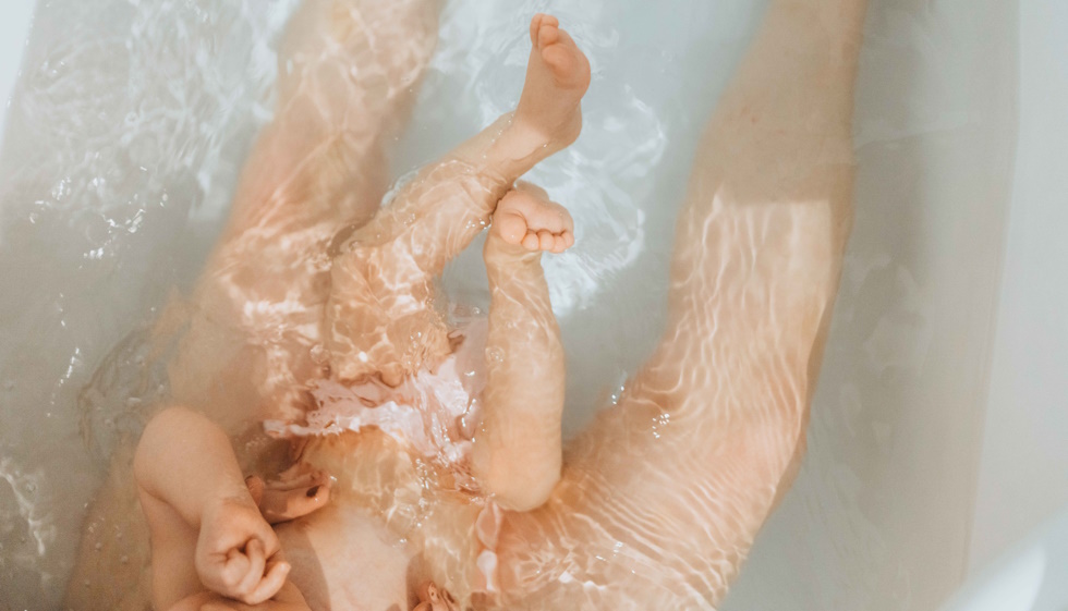 Jambes de bébé et sa maman dans un bain d'eau thermale
